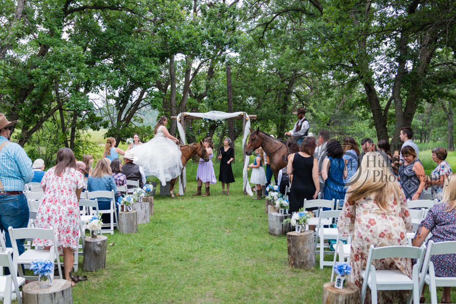 Bride and groom riding horses at wedding ceremony